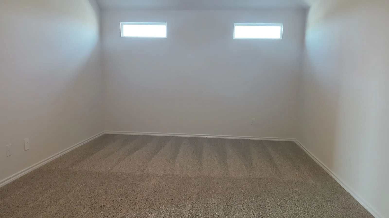 Textured carpeting, neutral wall paint, and two high-set rectangular windows