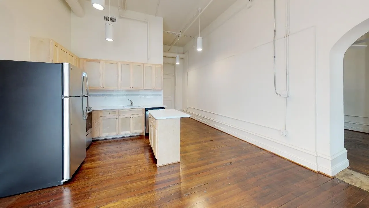 Kitchen featuring backsplash, dark wood-type flooring, stainless steel refrigerator, and a kitchen island