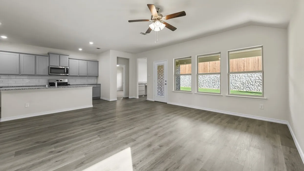 Open-concept living area featuring wood-finish flooring, a vaulted ceiling, and a ceiling fan with integrated lighting
