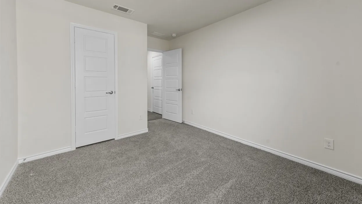 Spacious room featuring neutral carpeting, light-toned walls, and multiple paneled doors