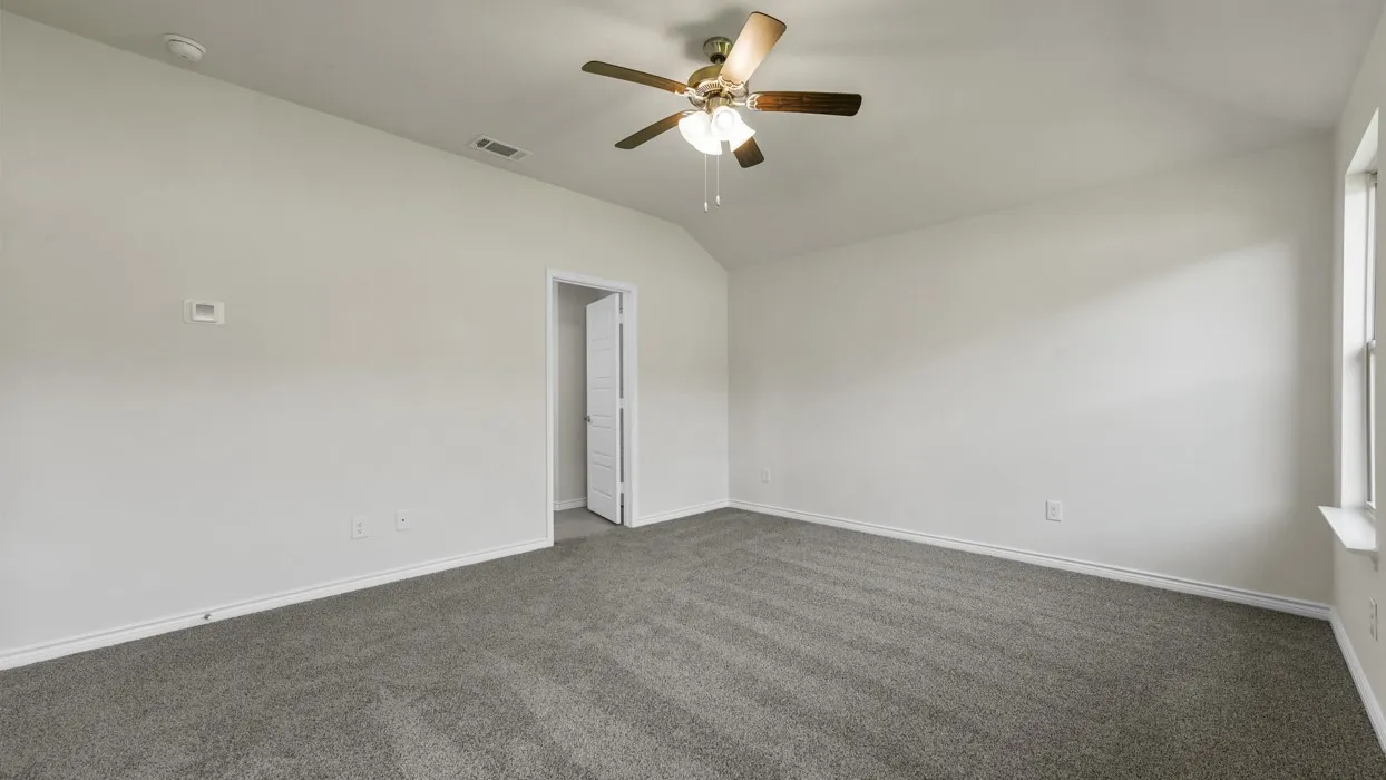 Spacious room featuring neutral carpeting, light-colored walls, and a ceiling fan with integrated lighting