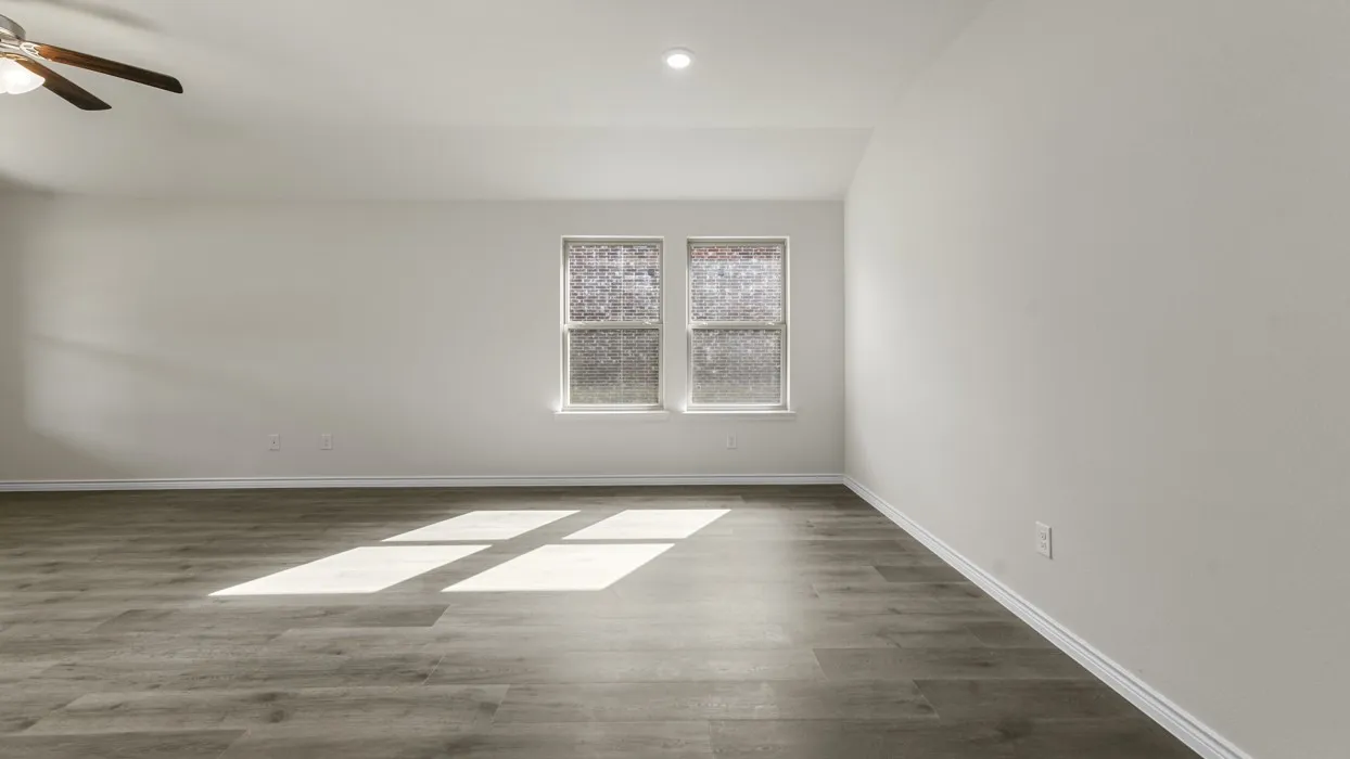 Spacious room featuring wood-finish flooring, light-toned walls, and a ceiling fan with integrated lighting