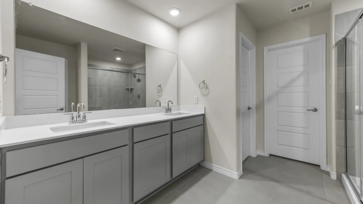 Double vanity with light gray shaker-style cabinetry, white countertops, dual undermount sinks, and chrome fixtures
