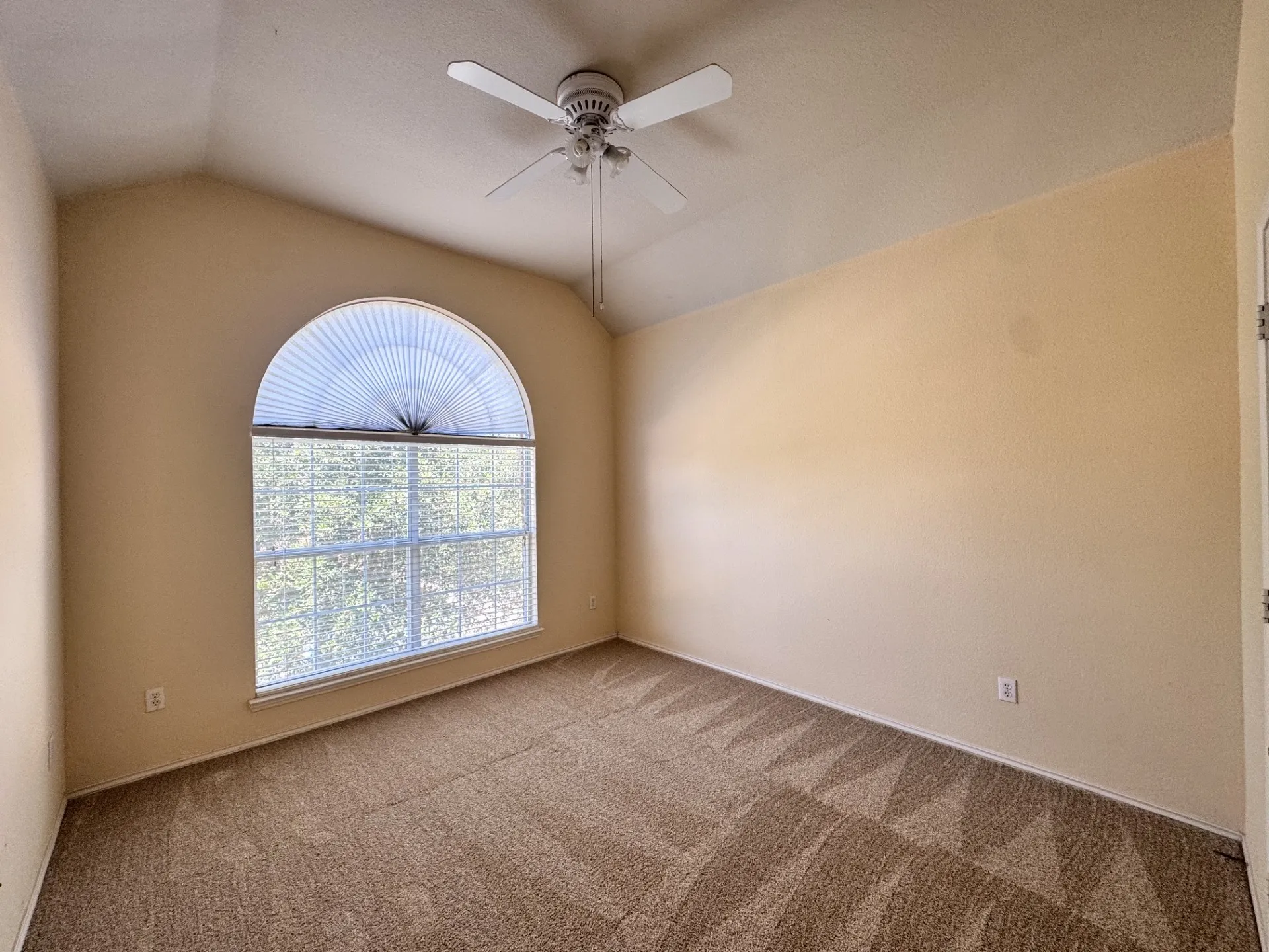 Vaulted ceiling with an arched window, ceiling fan, and carpeted flooring