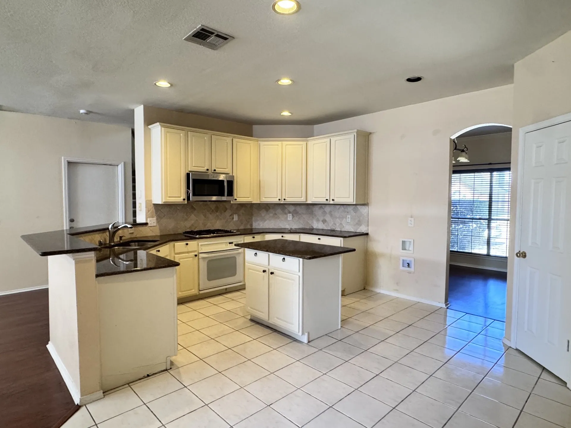 Kitchen featuring recessed lighting, tile flooring, an island, built-in appliances, and a tile backsplash