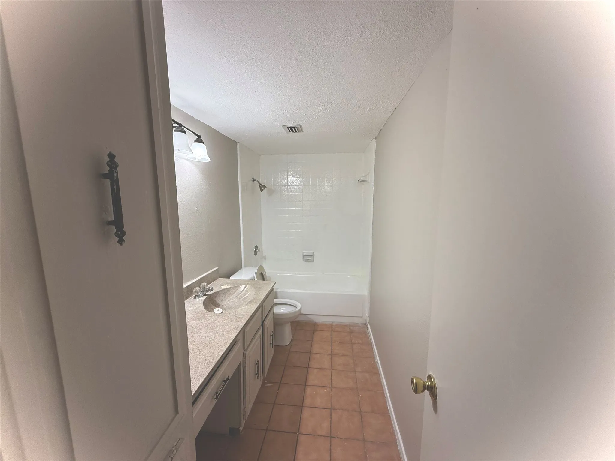 Bathroom featuring a vanity with an integrated sink, built-in lower cabinetry, a combination shower and tub, and tile flooring
