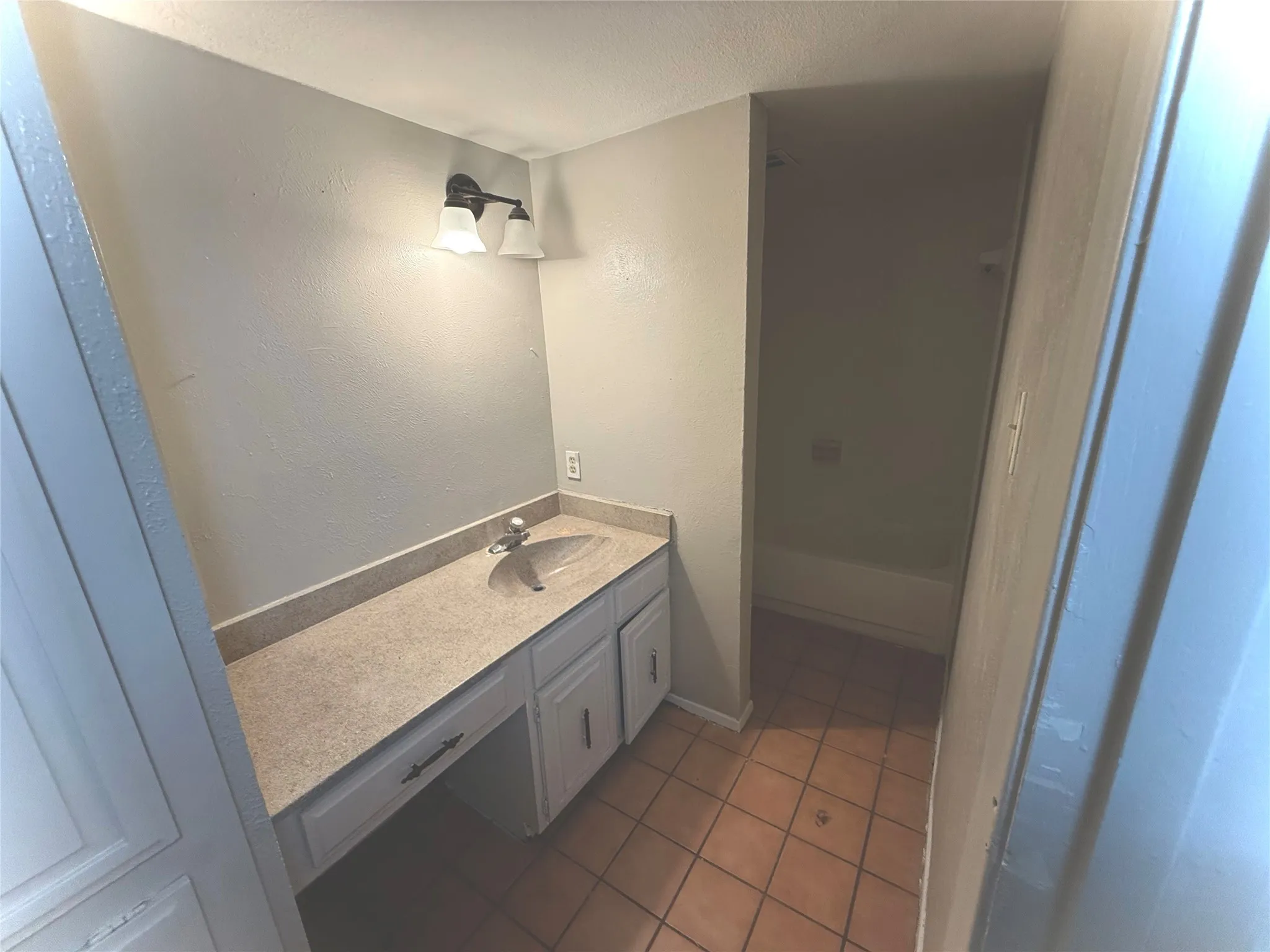 Bathroom featuring a vanity with an integrated sink, built-in cabinetry, and a bathtub with shower