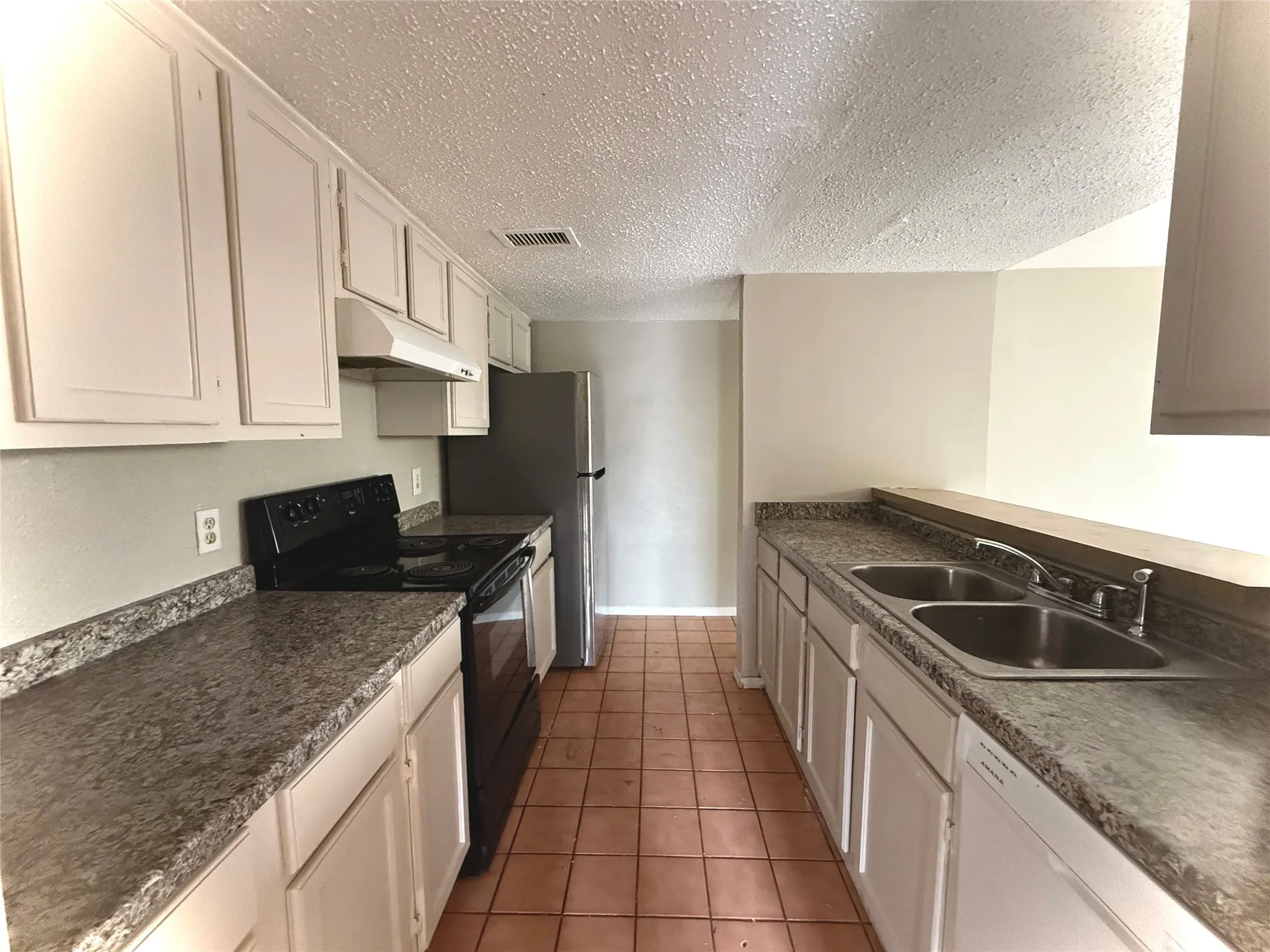 Kitchen featuring white cabinetry, a double basin sink, black electric range, and light-toned countertops