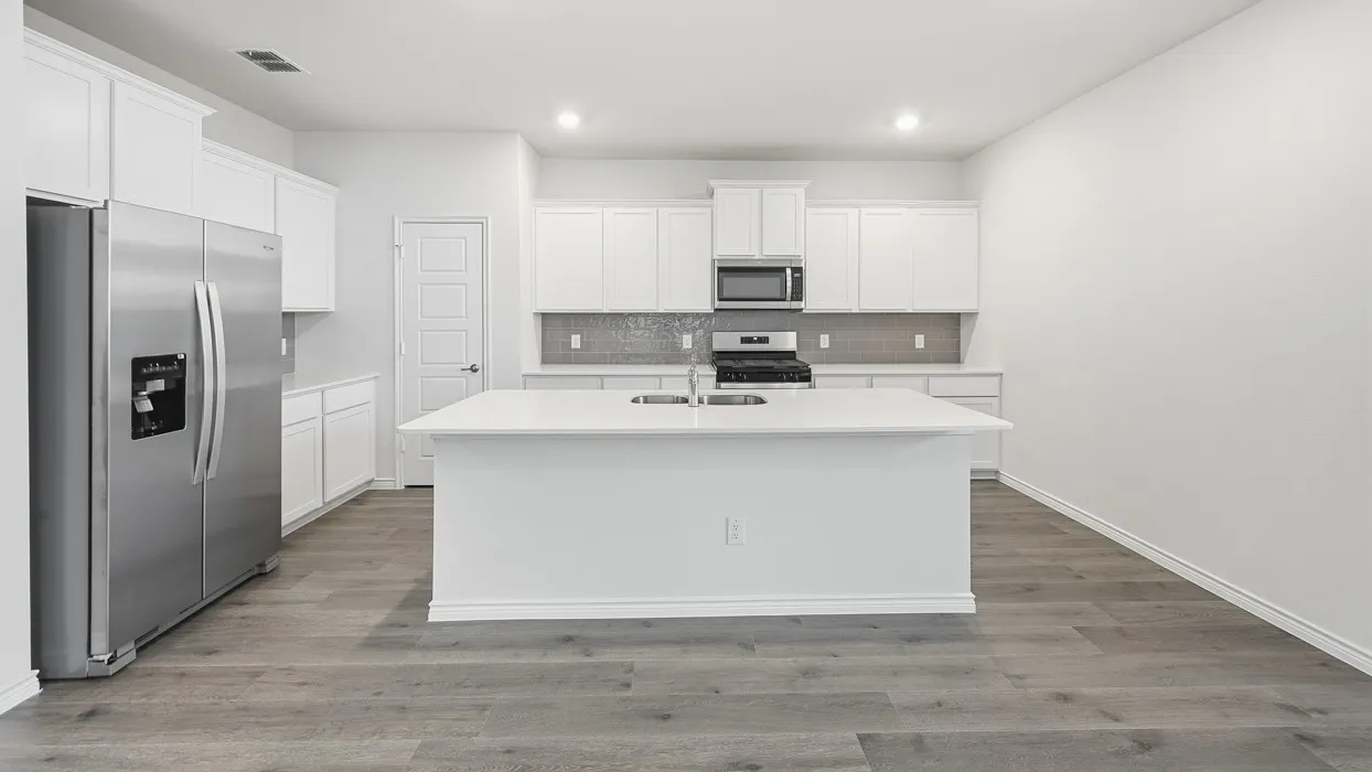 Contemporary kitchen featuring a large central island with an undermount sink, stainless steel appliances, white cabinetry, and wood-finish flooring
