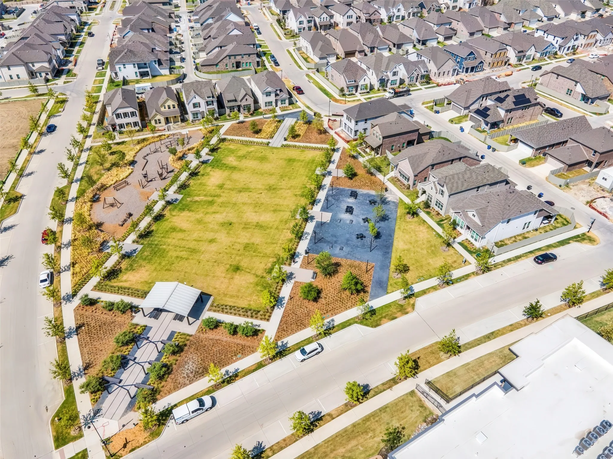 Community green space featuring a large lawn, integrated playground, and covered seating area