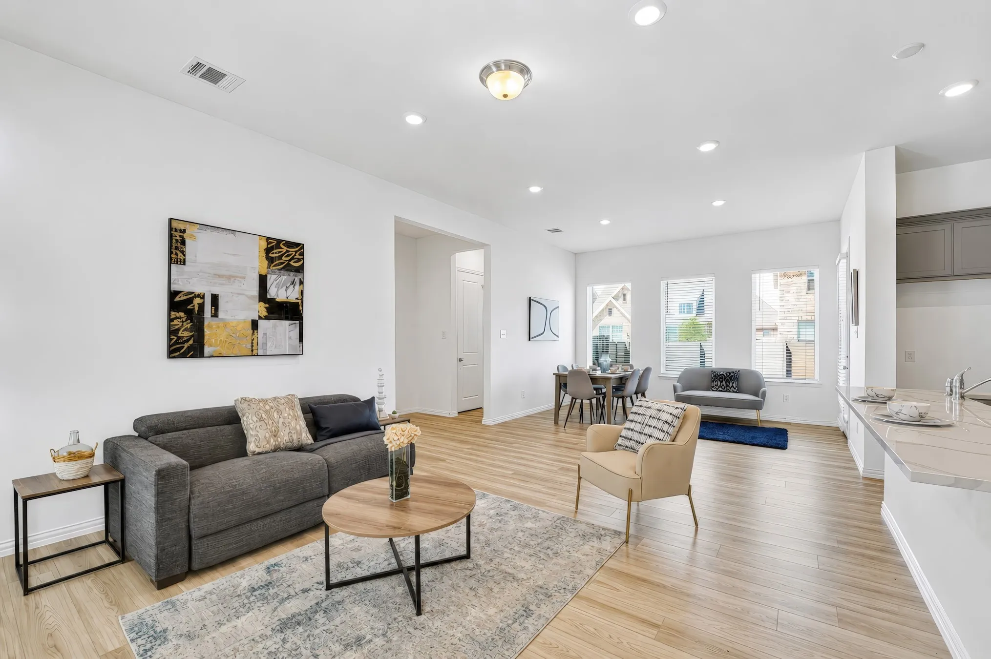 Open-concept living space with wood-finish flooring, recessed lighting, and multiple windows providing natural illumination
