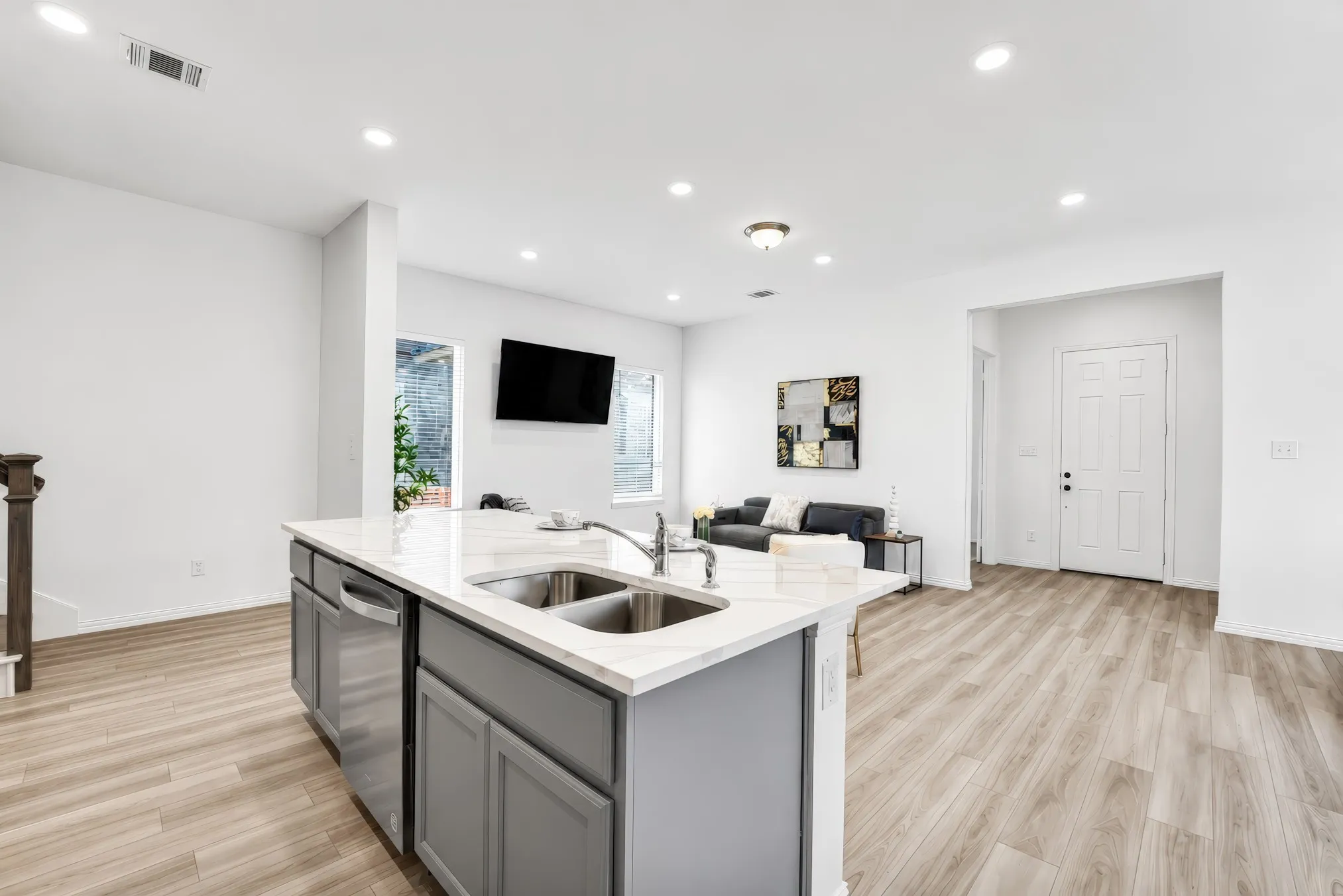 Kitchen island with a double basin sink, stainless steel appliances, and light-toned countertops
