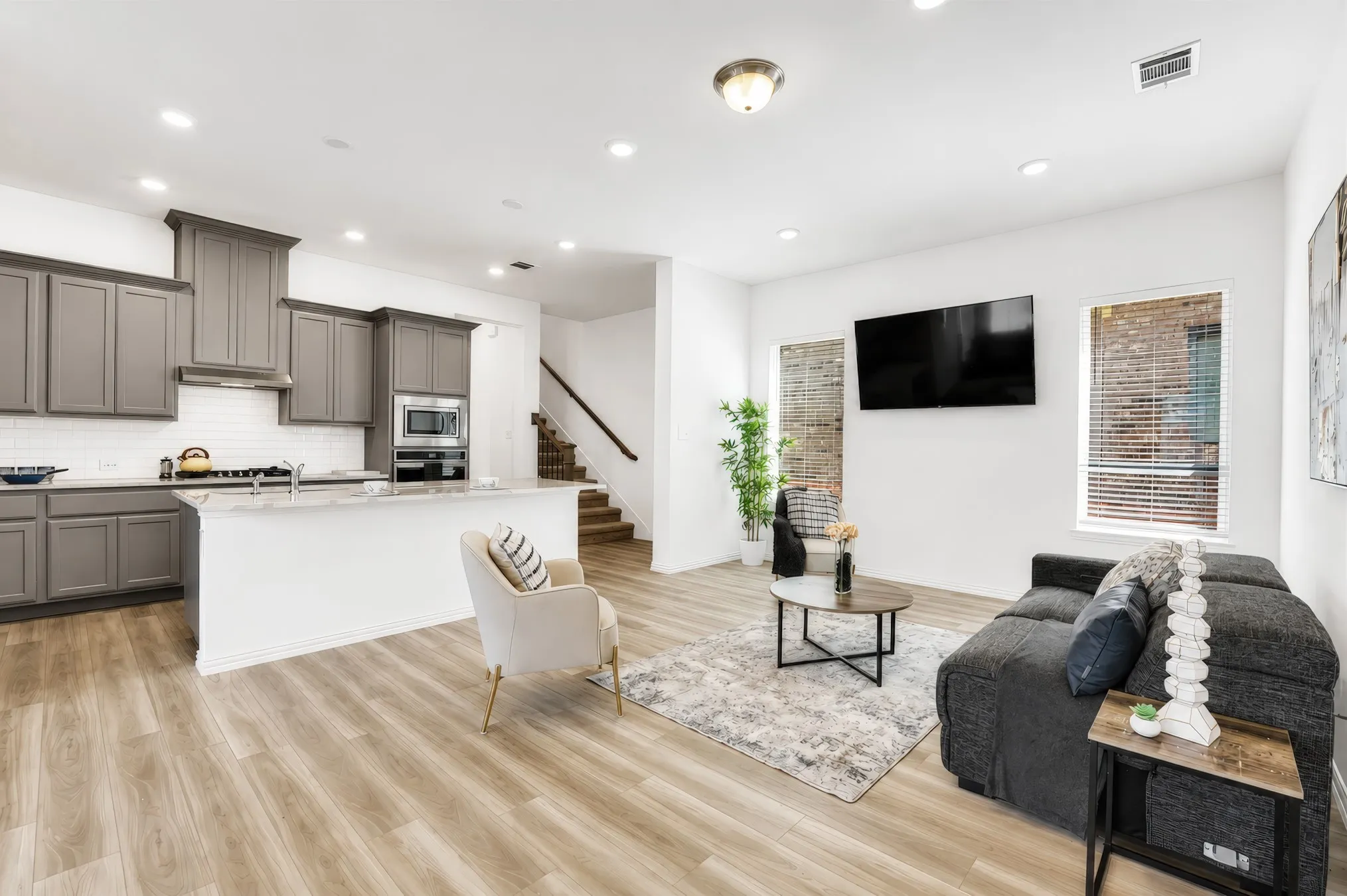 Open-concept living area featuring wood-finish flooring, recessed lighting, and a white subway tile backsplash in the kitchen