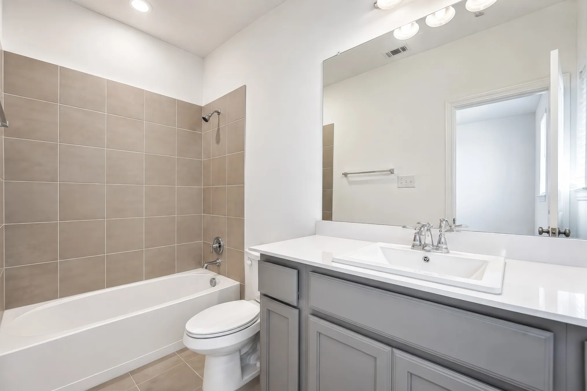 Full bathroom featuring a rectangular drop-in sink, white countertop, gray vanity cabinetry, and a chrome faucet