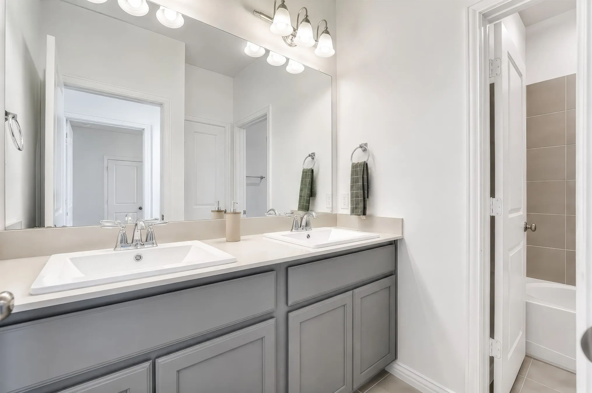 Double vanity with integrated sinks, light-toned countertop, and gray wood-finish cabinetry