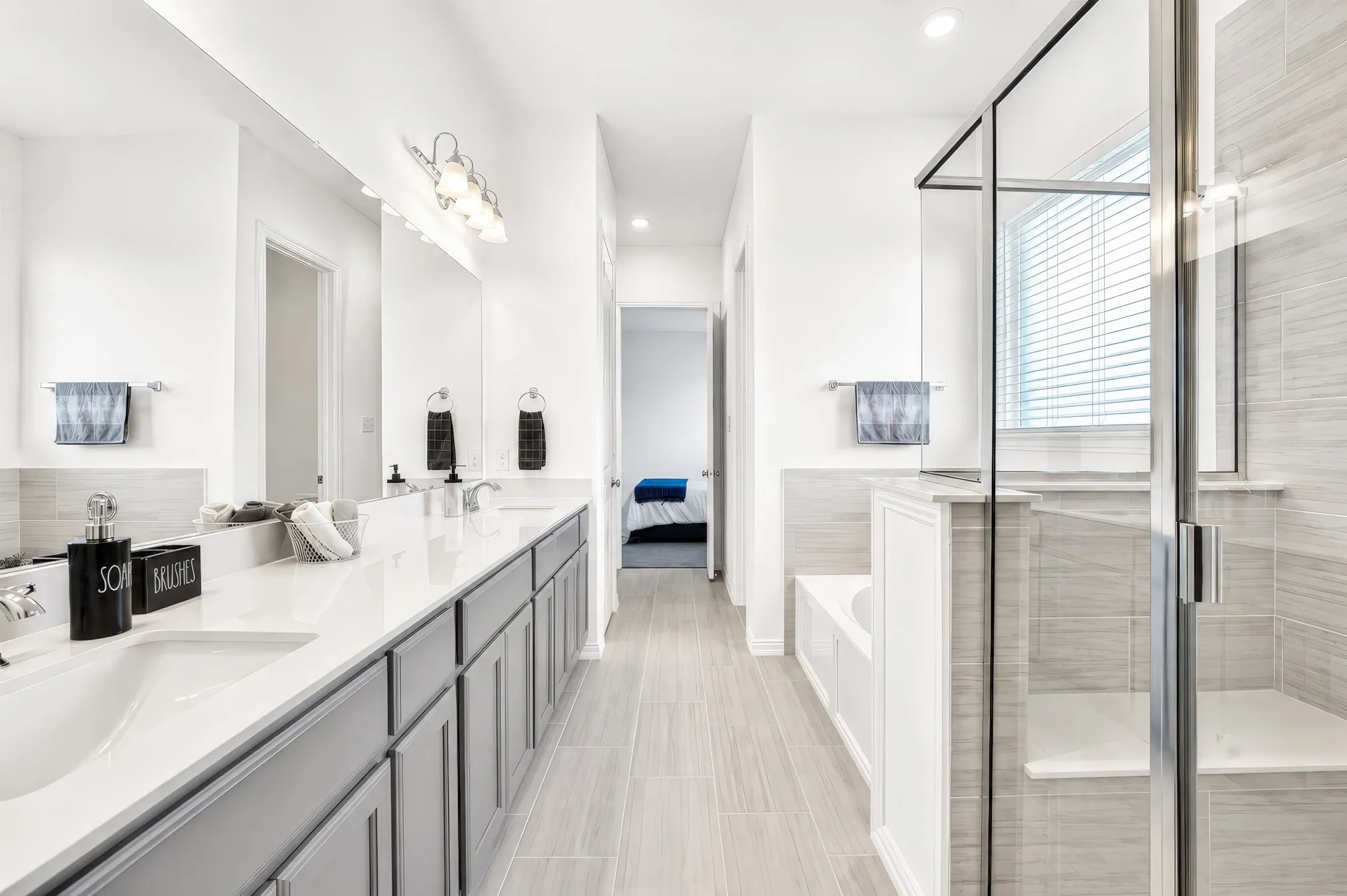Dual vanity with undermount sinks, an expansive mirror, and sconce lighting