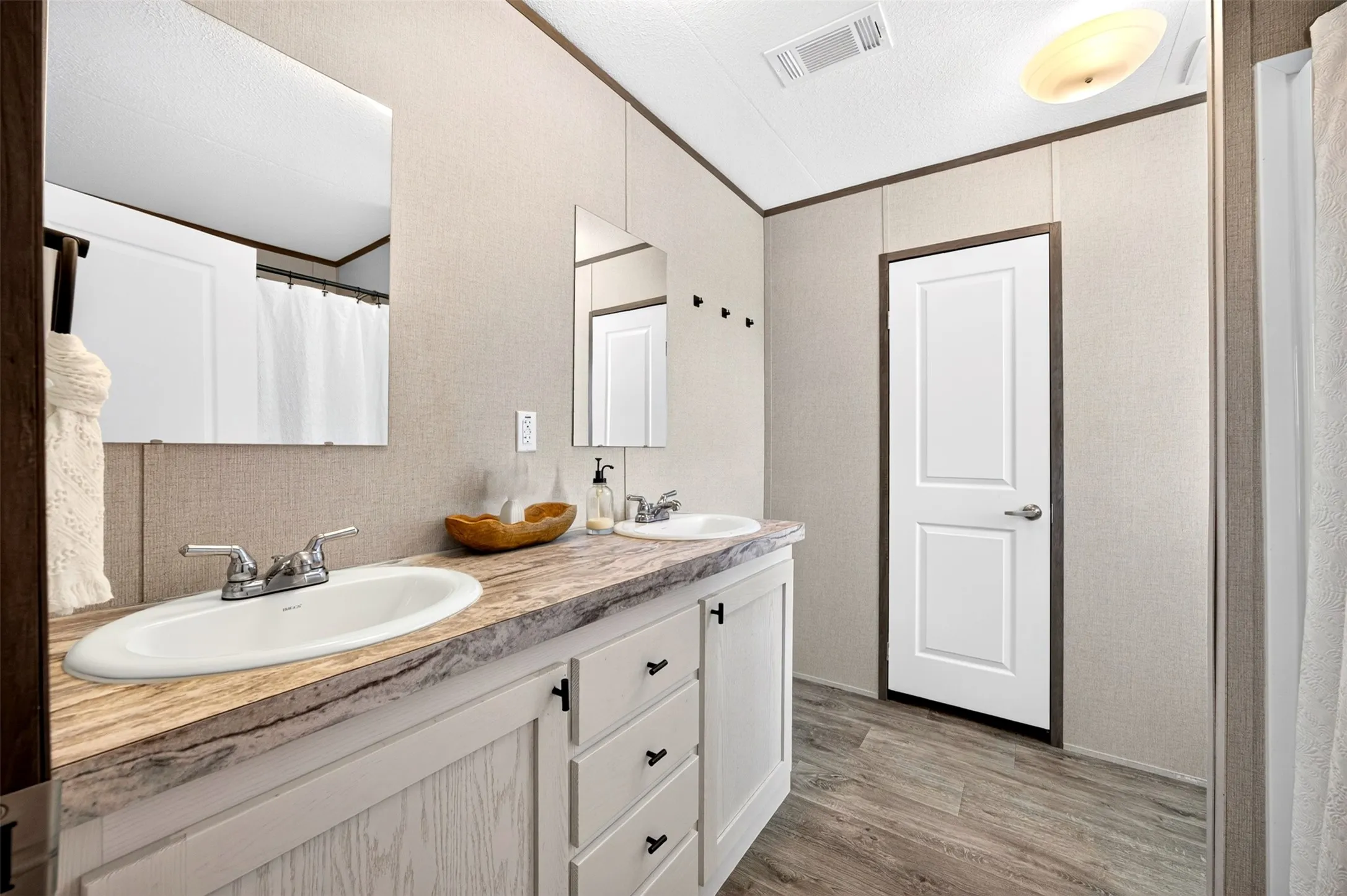 Dual vanity with integrated sinks, stone-look countertop, wood-finish flooring, and panel interior door