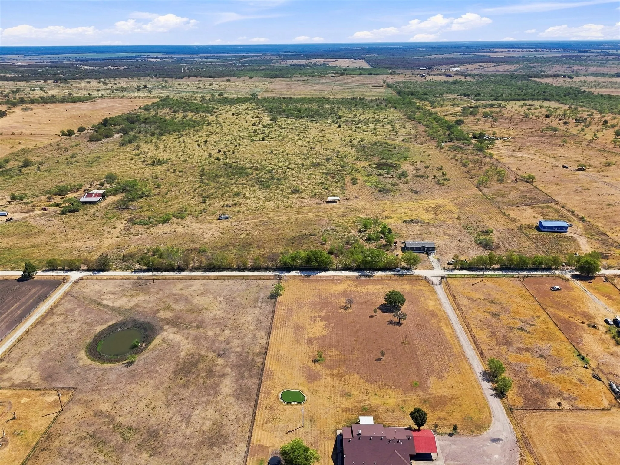 Expansive rural landscape featuring scattered structures, multiple ponds, and varied terrain