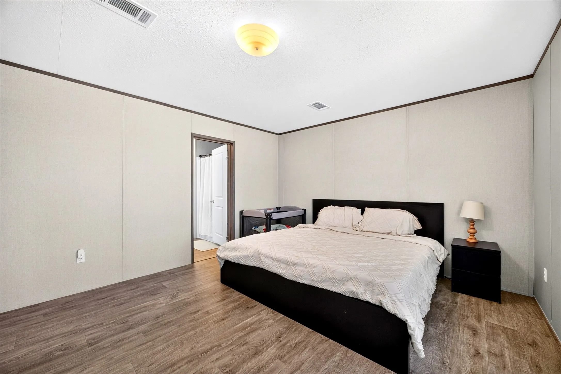 Wood-finish flooring with a neutral wall paneling and dark trim