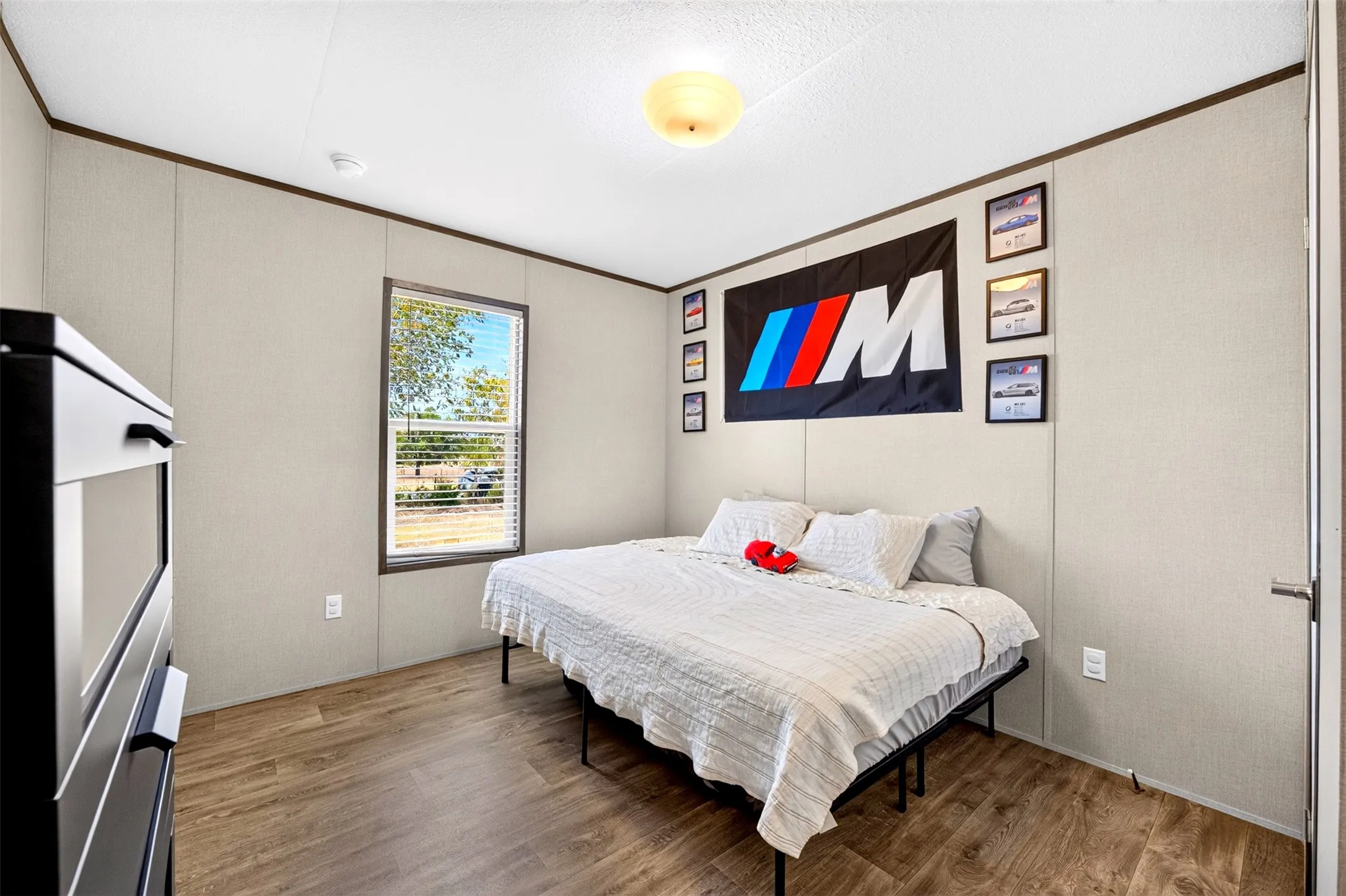 Wood-finish flooring, a ceiling-mounted light fixture, and a window with blinds