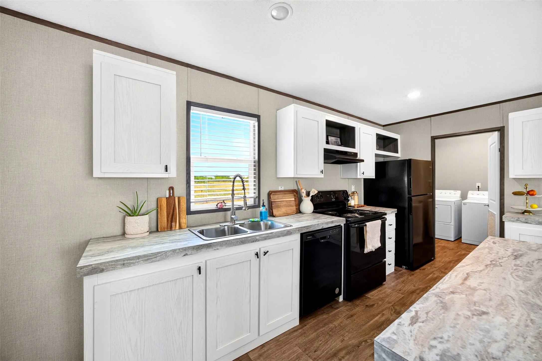 Kitchen with white cabinetry, wood-finish flooring, and a stainless steel double basin sink