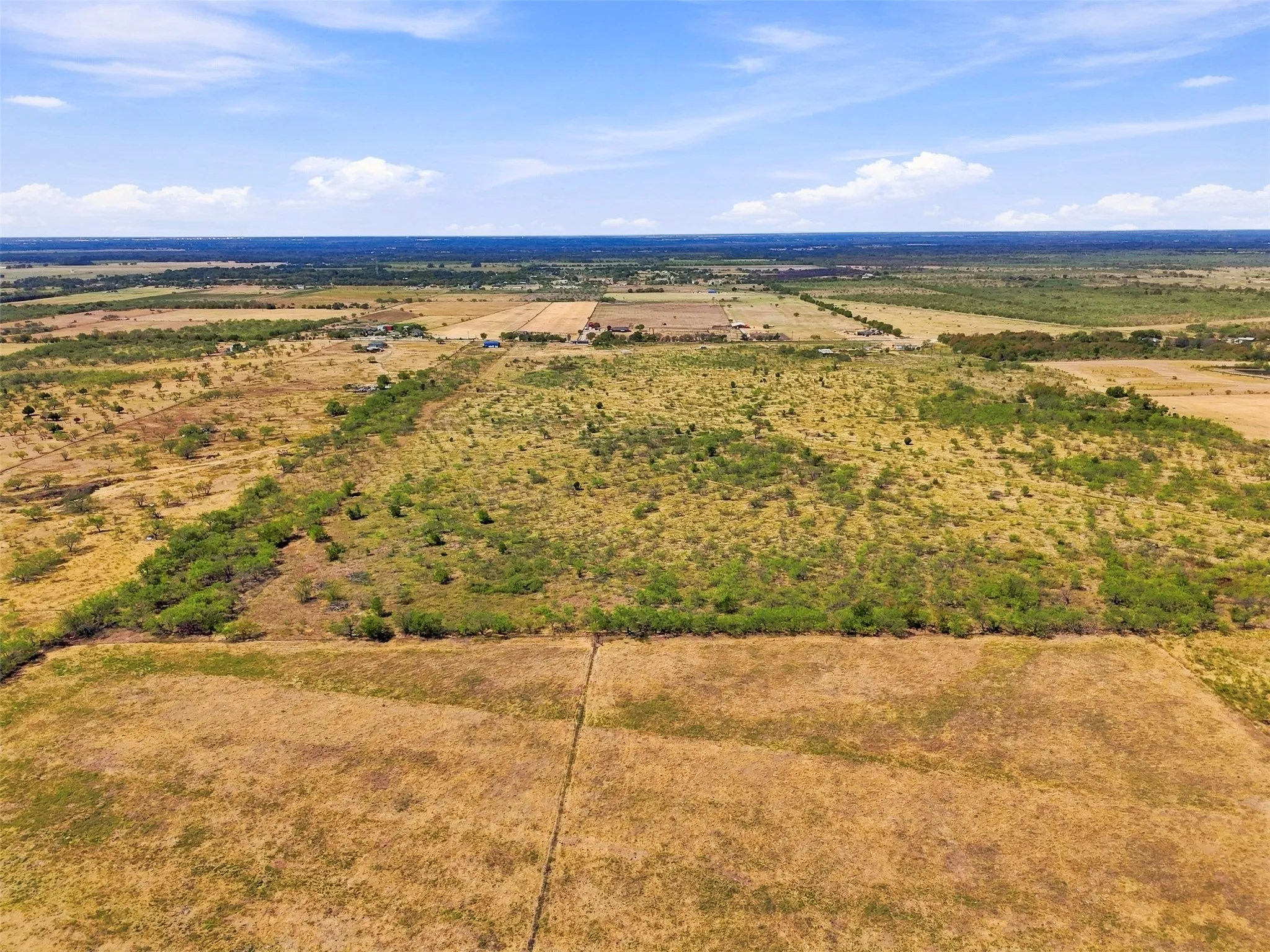 Expansive rural landscape featuring a mix of open fields and natural vegetation under a clear sky
