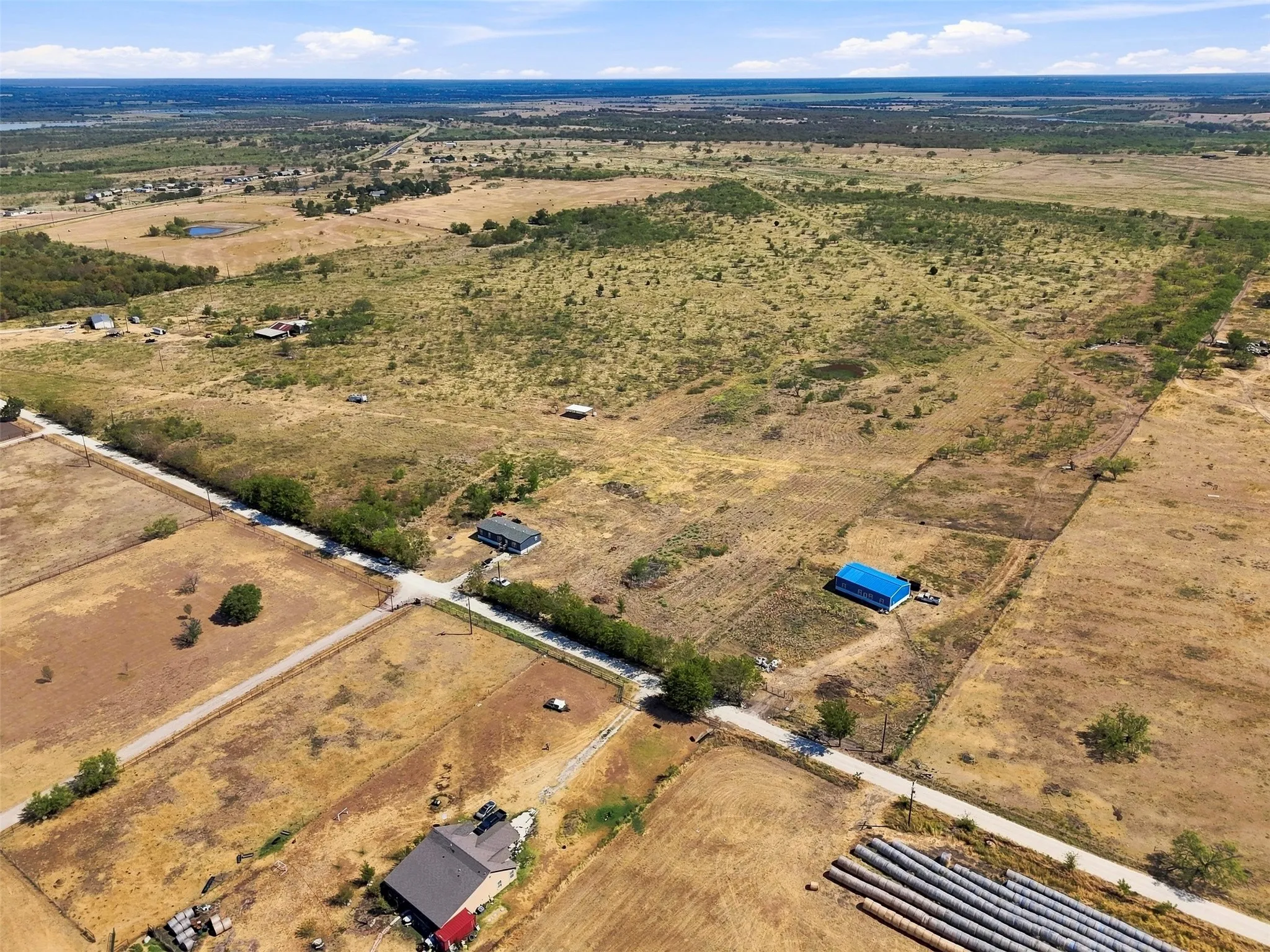 Expansive rural acreage with multiple structures, including a primary residence, a blue-roofed outbuilding, and additional peripheral buildings