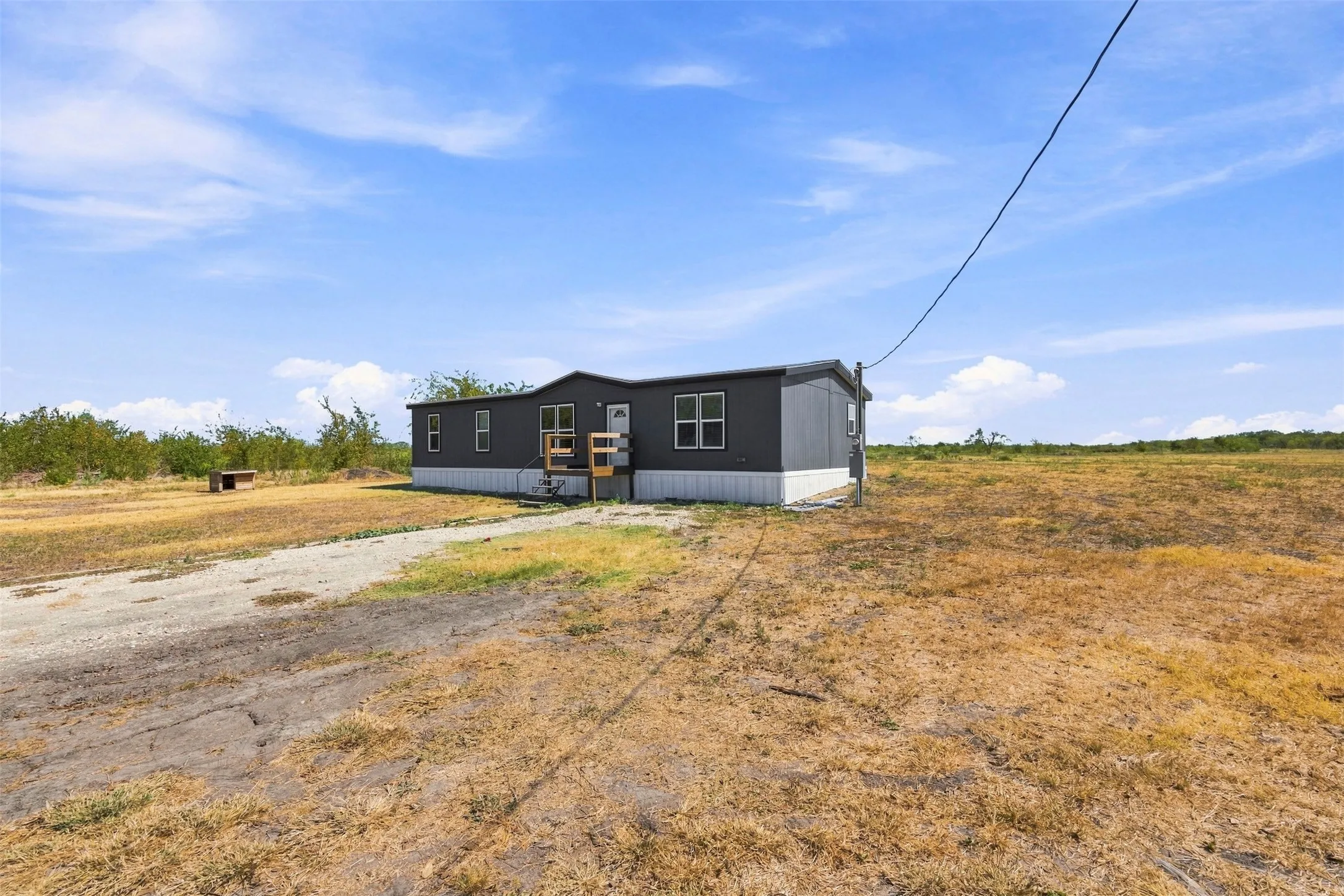 Manufactured home with dark gray siding, white trim, and multiple windows