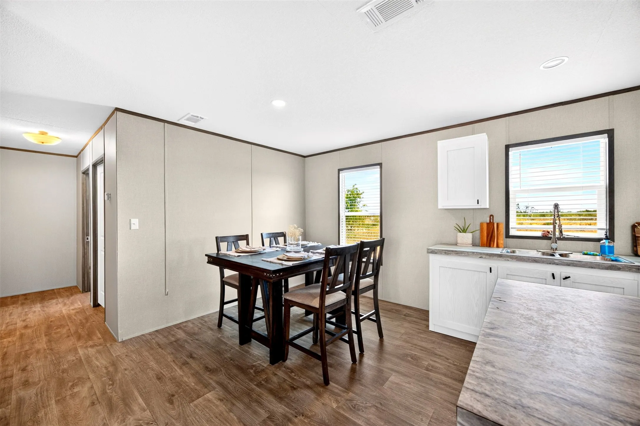 Open-concept living space with wood-finish flooring, recessed ceiling lighting, and white cabinetry