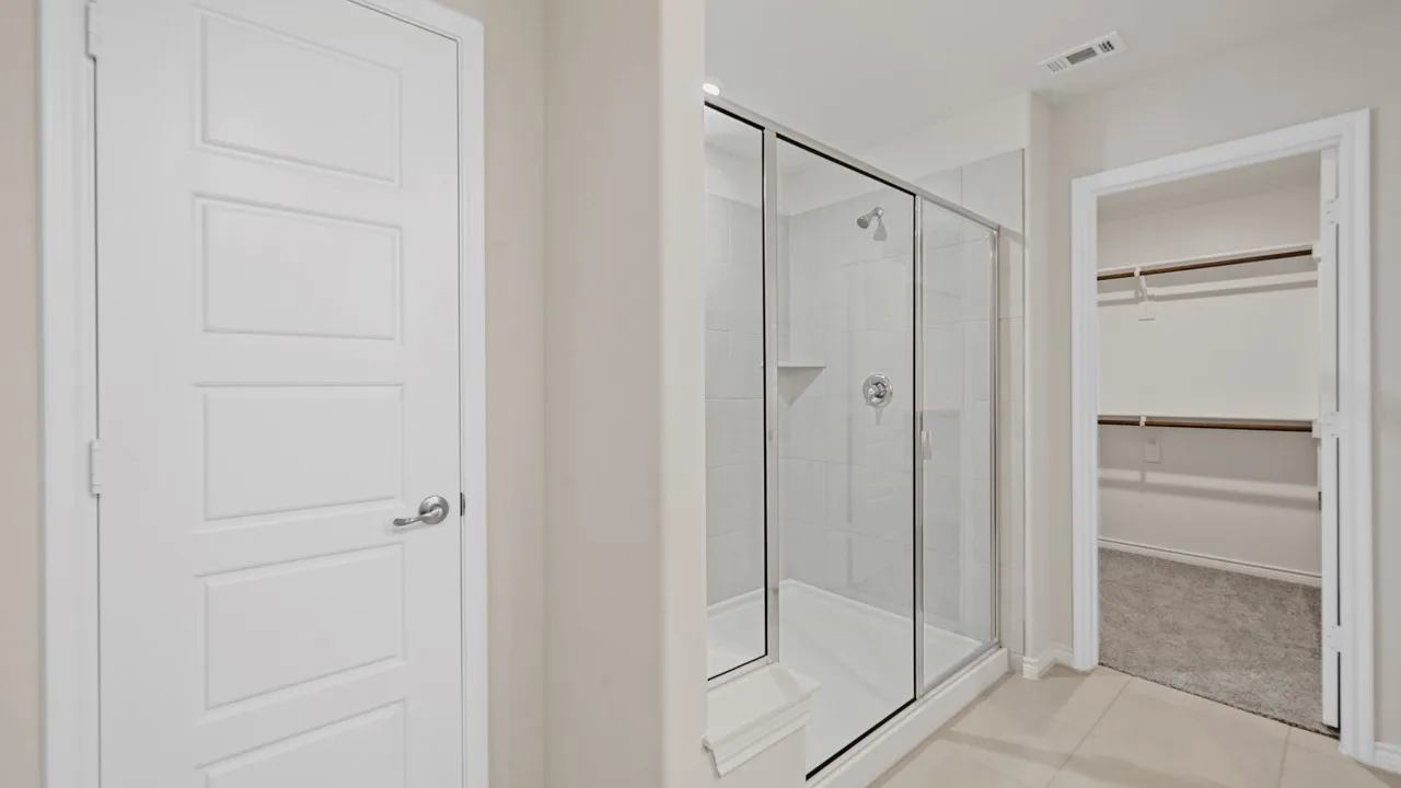 Shower with a glass enclosure, tiled walls, and a built-in shelf
