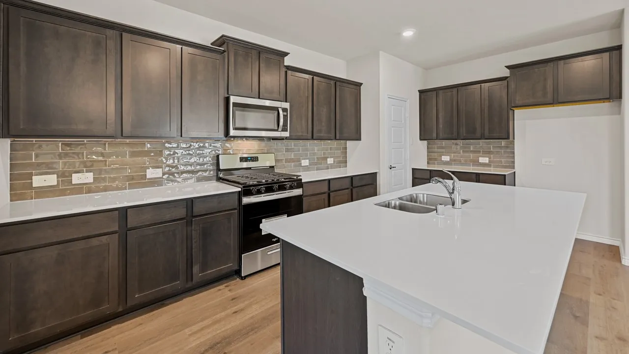 Kitchen featuring dark wood-finish cabinetry, light-toned countertops, and a full stainless steel appliance package