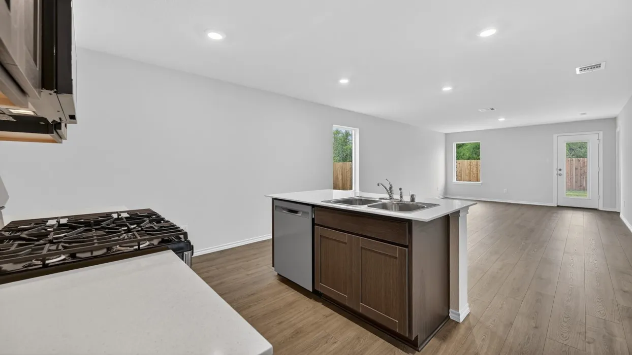 Kitchen island with dual stainless steel sink, wood-finish cabinetry, and integrated dishwasher