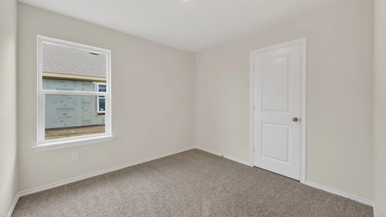 Neutral-toned carpeting, white interior door with polished hardware, white trim, and a white-framed window