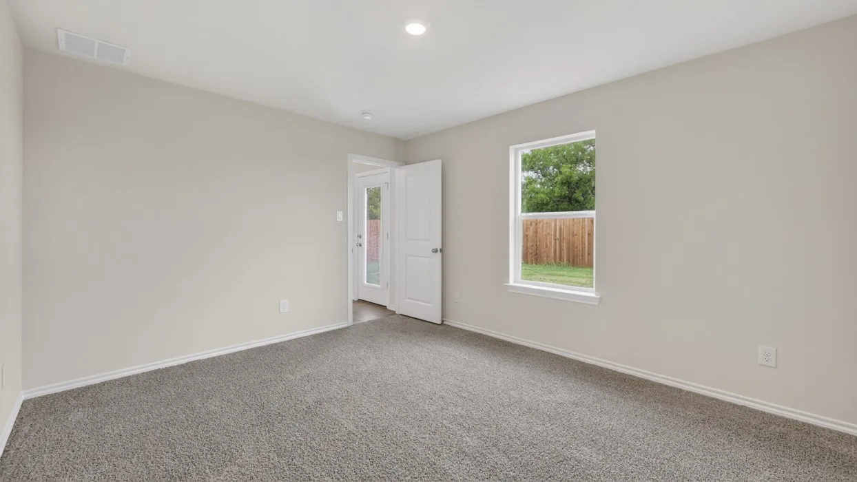 Neutral wall paint, carpet flooring, a window with exterior visibility, and a solid door with a frosted glass panel