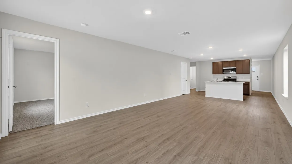 Open-concept living area featuring wood-finish flooring, recessed lighting, and a kitchen island with white cabinetry