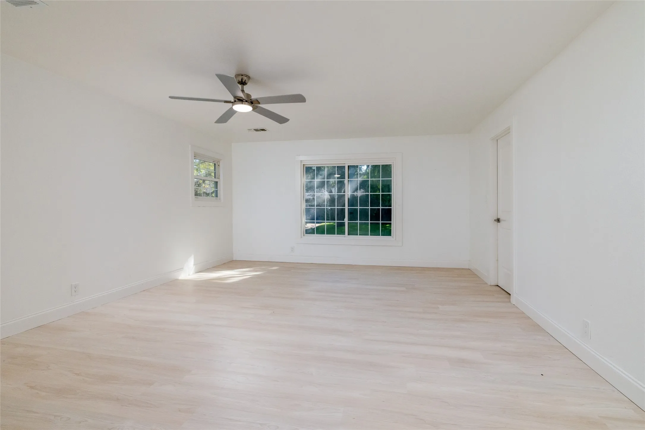 Bright interior featuring wood-finish flooring, a ceiling fan, and multiple windows
