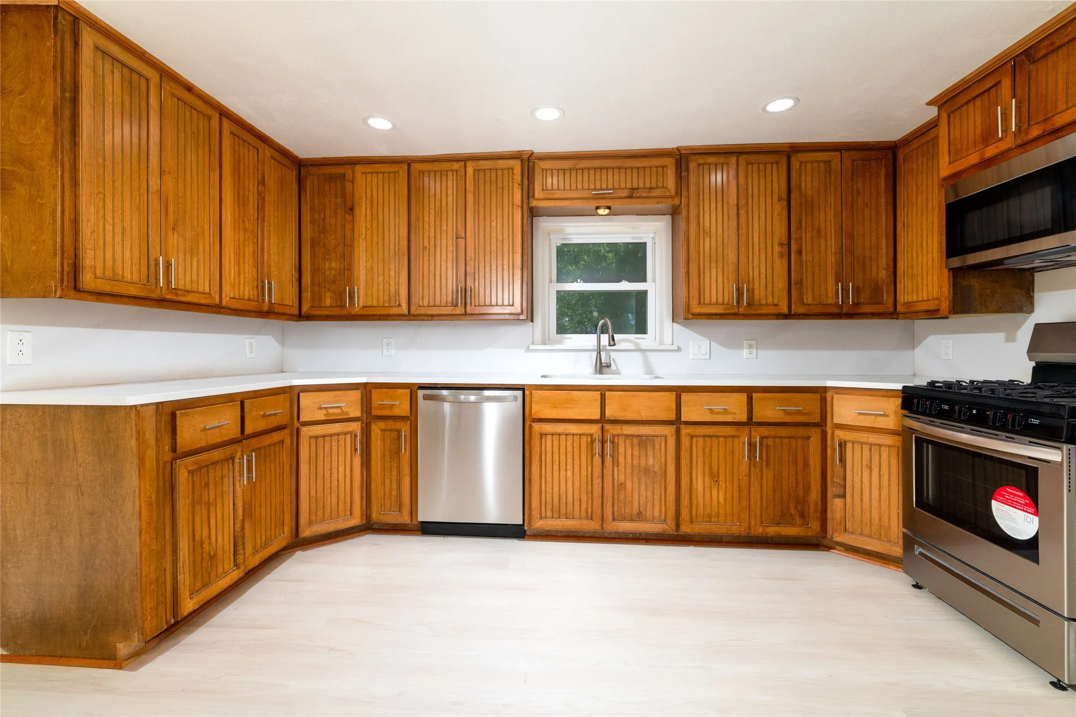 Kitchen with extensive wood cabinetry, white countertops, a stainless steel dishwasher, a stainless steel range, and a stainless steel microwave