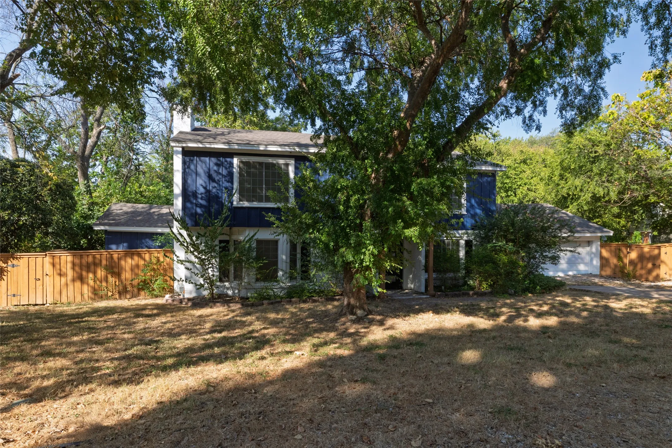 Two-story exterior with dark blue siding, a peaked roof, and a white chimney