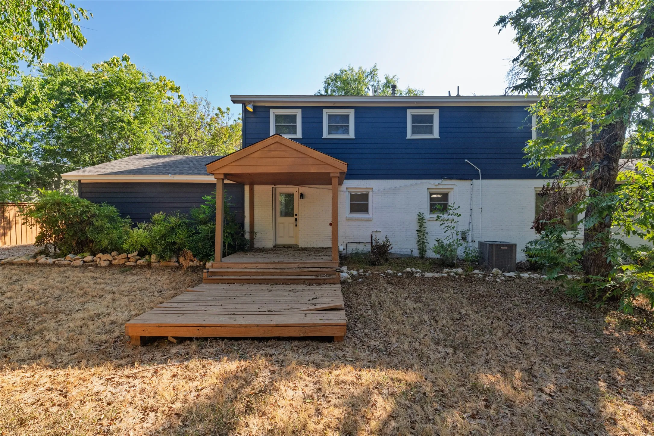 Two-story residence featuring blue siding and white brick, with a covered wood deck
