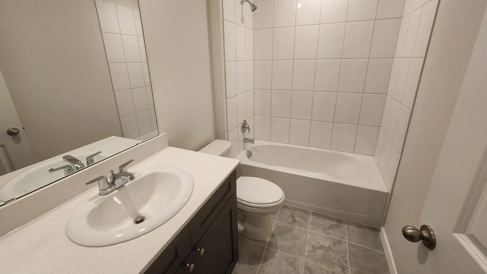 Vanity with integrated sink, chrome faucet, and expansive wall mirror