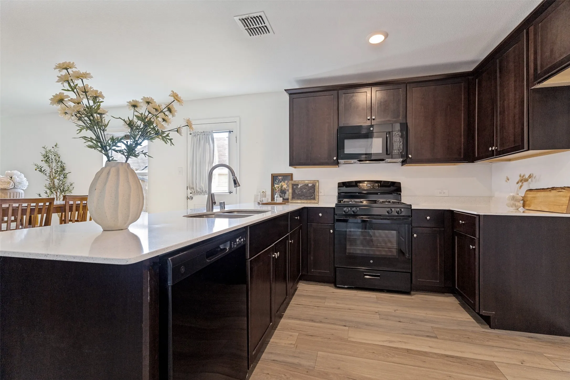 Kitchen featuring wood-finish flooring, dark wood cabinetry, white countertops, and stainless steel appliances
