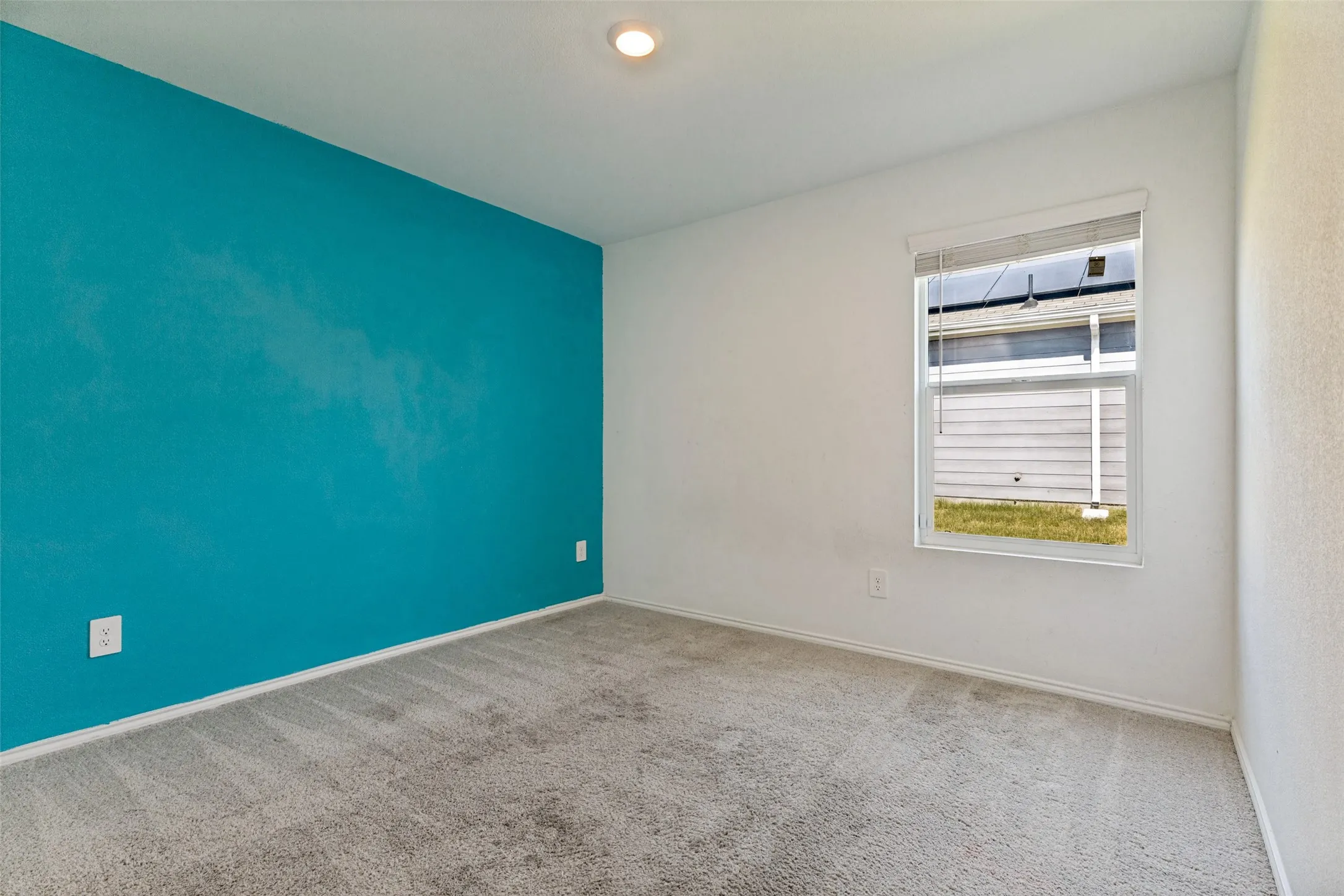 Recessed ceiling light, single window, white window blinds, turquoise accent wall, carpeted flooring