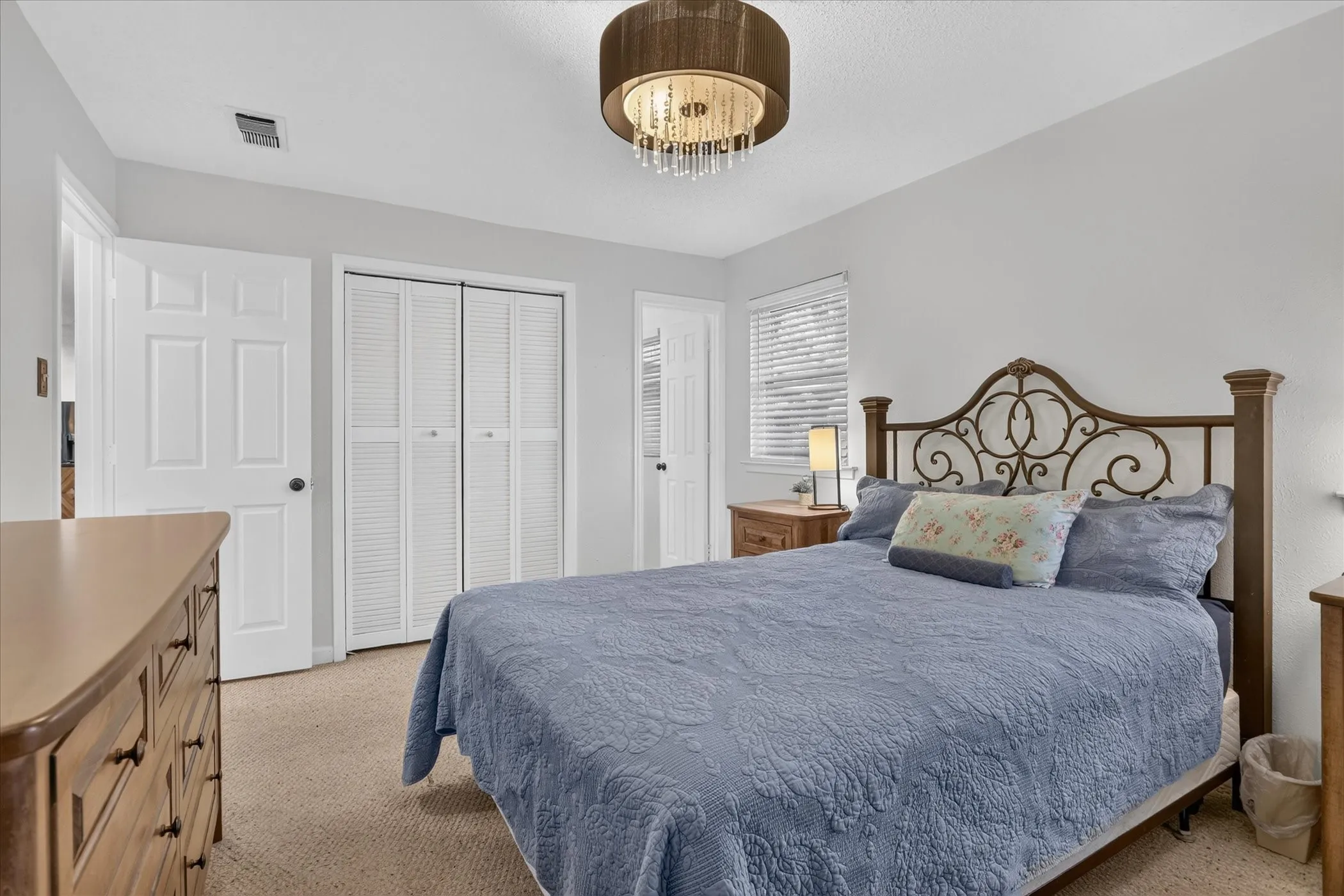 Textured carpet flooring, white interior doors, bifold closet doors, and a chandelier-style ceiling light fixture