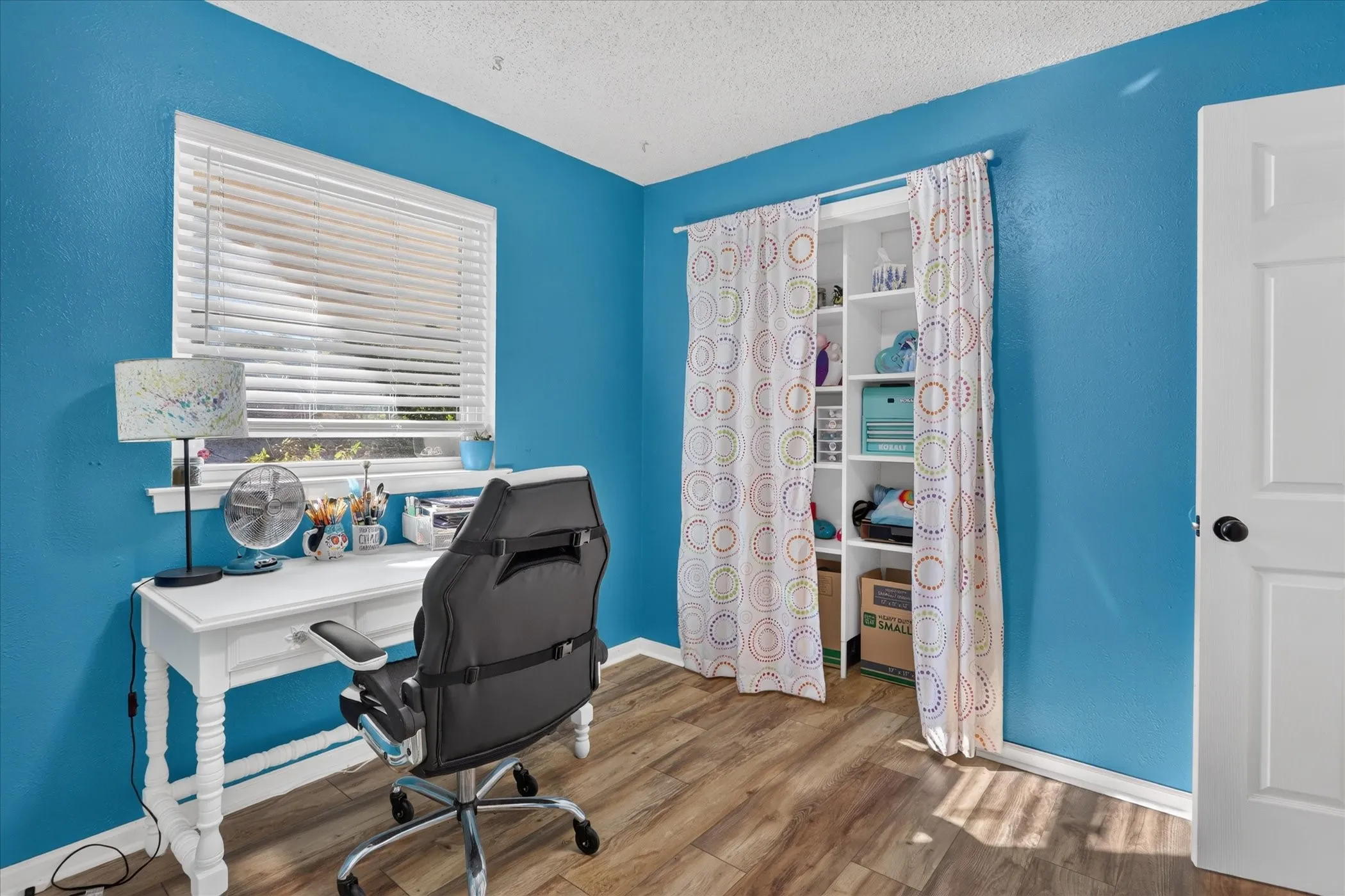 Wood-finish flooring, built-in shelving, window with blinds, and paneled interior door