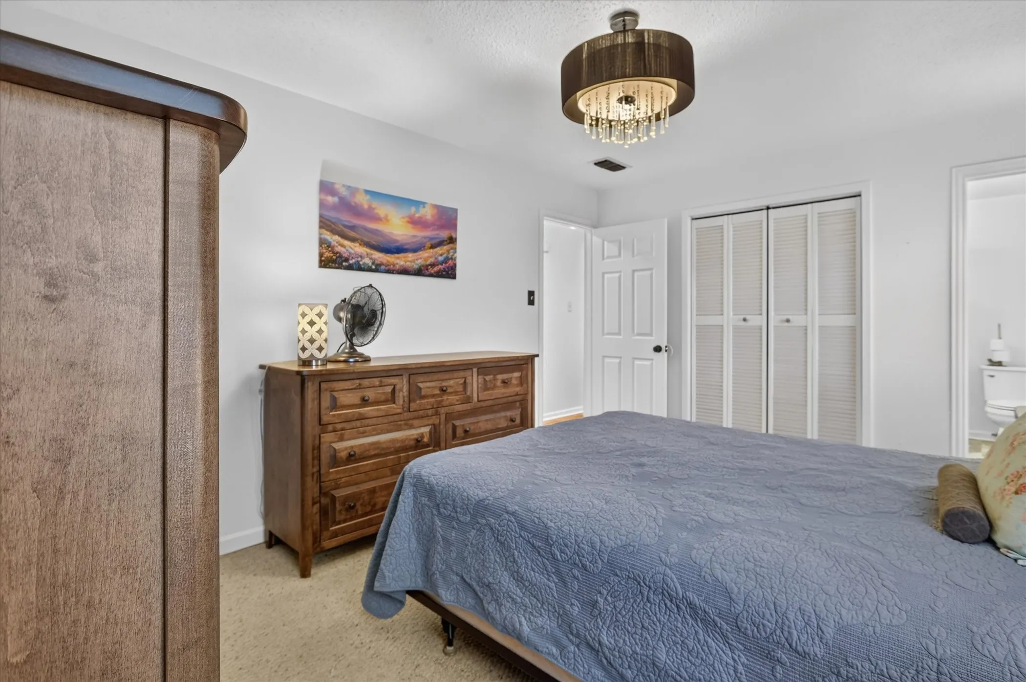 Ceiling-mounted chandelier with crystal accents, white paneled doors, and bifold louvered closet doors