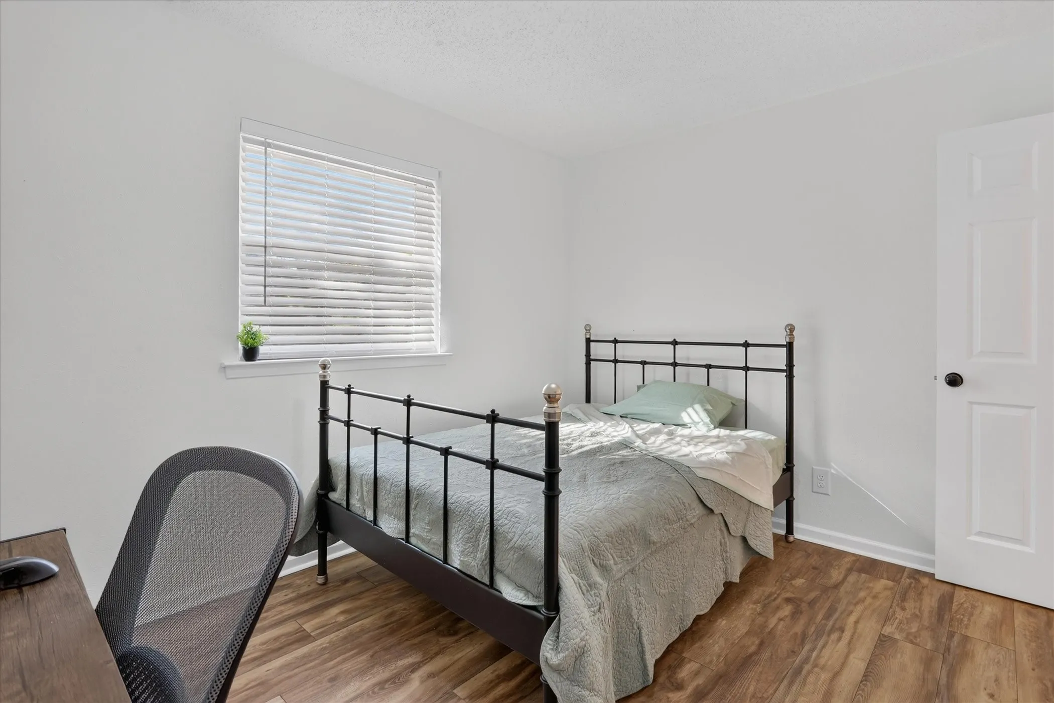 Bright interior with wood-finish flooring, white walls, and a window with blinds