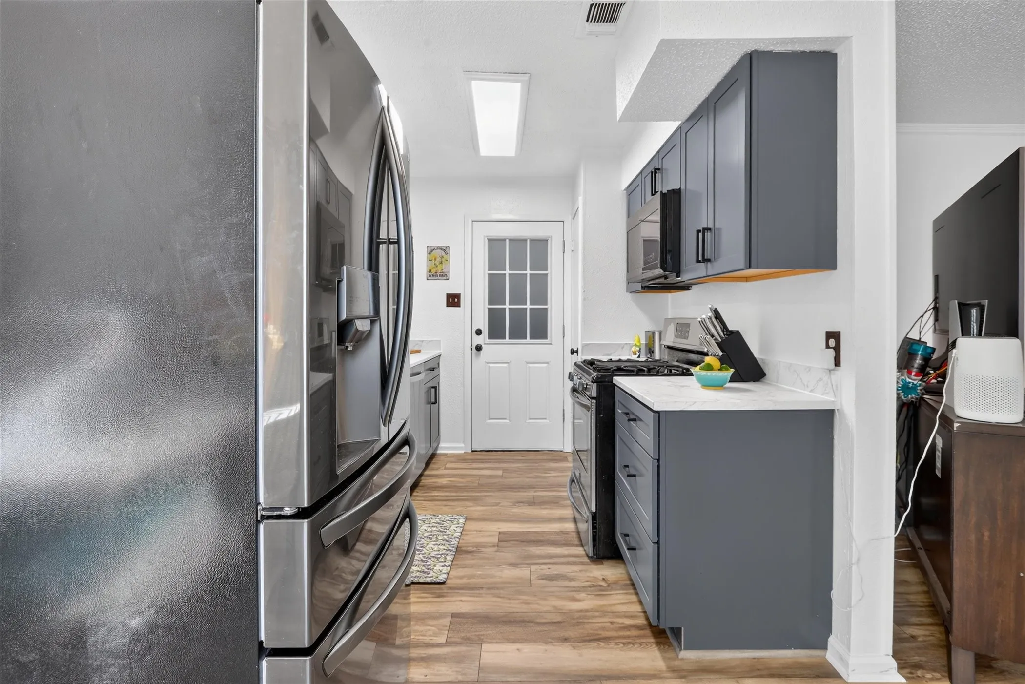 Kitchen featuring wood-finish flooring, white countertops, gray cabinetry, and a white paneled door