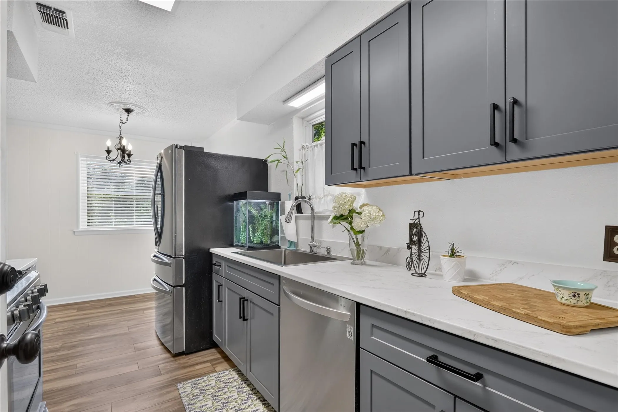 Kitchen featuring gray shaker-style cabinetry, stainless steel appliances, a stainless steel sink, and light-toned countertops