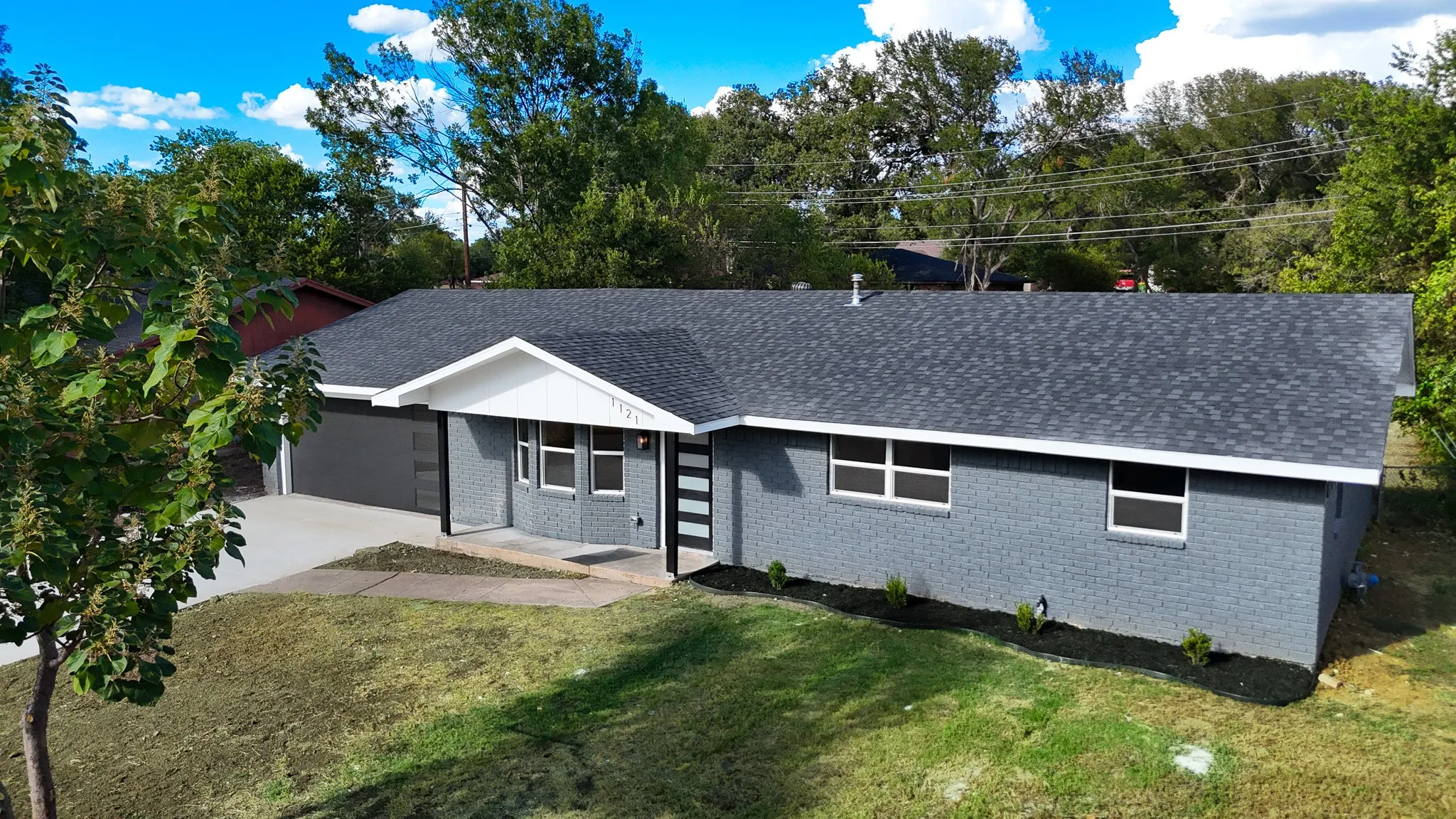 Contemporary exterior with gray brick, dark gray shingle roof, white trim, and a modern entryway