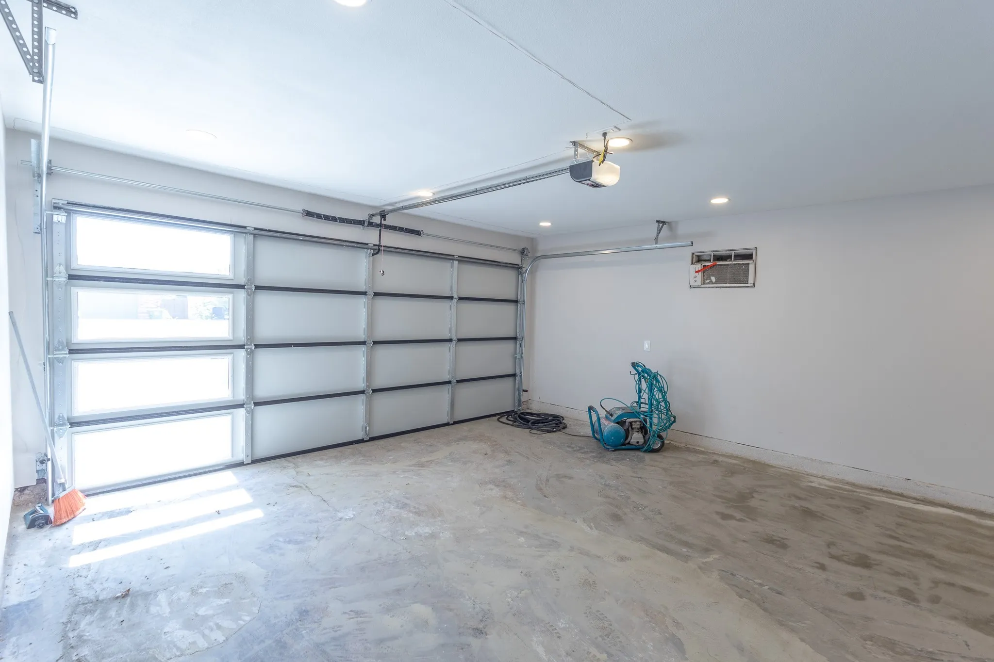 Overhead garage door with frosted glass panels, automatic garage door opener, recessed lighting, and a concrete floor